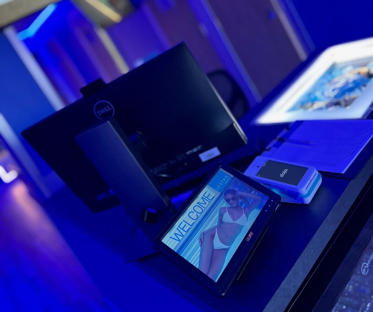 Lilliput UM1010 point of sale monitor at a Lextan tanning salon reception showing a welcome screen